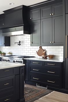 a kitchen with black cabinets and white subway backsplash