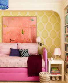 a pink couch sitting in front of a book shelf