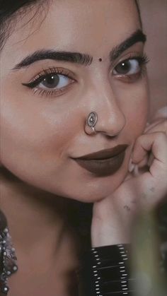 a close up of a person with a nose ring and piercing on her nose, looking at the camera