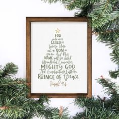 a cross - stitch christmas tree is hanging on the wall next to some pine branches