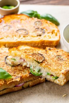 two grilled sandwiches sitting on top of a cutting board next to dipping sauces