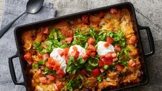 a casserole dish with tomatoes, sour cream and lettuce