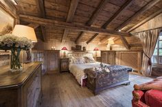 a bedroom with wooden walls and ceilings has a bed in the center, two lamps on either side