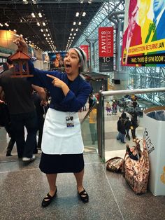 a woman in an apron pointing at something on the ground with her mouth wide open