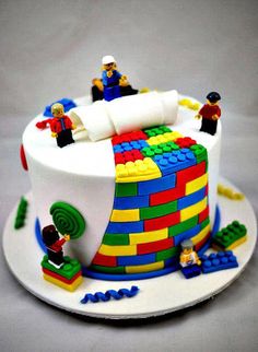 a birthday cake with legos on it and people around the cake, all made out of lego blocks