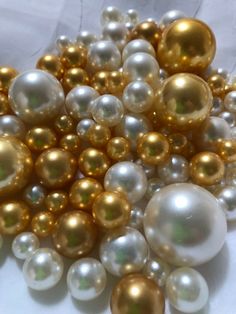 a pile of gold and white pearls on a tablecloth with other beads in the background