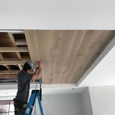 a man on a ladder working on a wooden ceiling