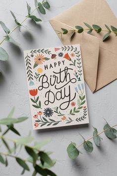 a card with the words happy birthday on it next to some leaves and envelopes