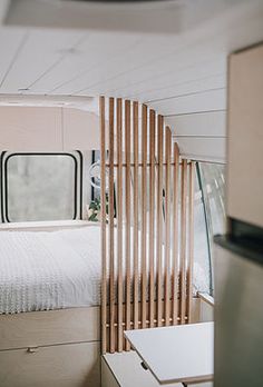 the interior of a camper with a bed, dressers and mirror in it