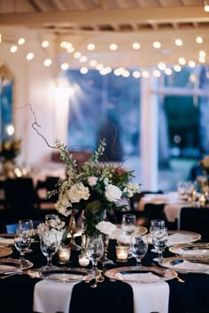 the table is set with black and white linens, silverware, and flowers