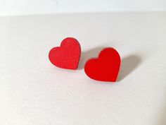 two red heart shaped earrings sitting on top of a white surface