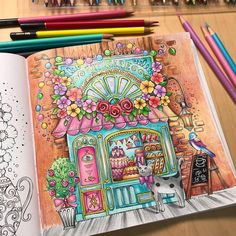 an open coloring book on a table with colored pencils