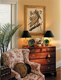 a living room filled with furniture and a painting on the wall over a chest of drawers