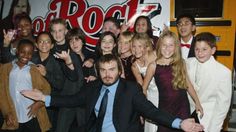 a group of people posing for a photo in front of a rock and roll sign