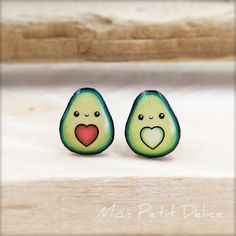 two avocado shaped earrings with hearts on them sitting on top of a table