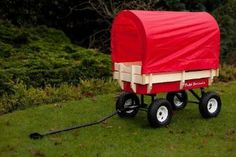 a red covered wagon sitting on top of a lush green field