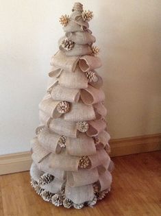 a christmas tree made out of burlocks and pine cones on a wooden floor