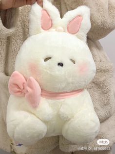 a person holding a white stuffed animal with pink ears