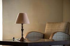 a lamp sitting on top of a wooden table next to a chair in a room