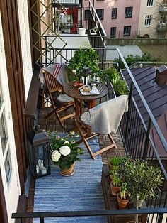 an apartment balcony with potted plants and chairs