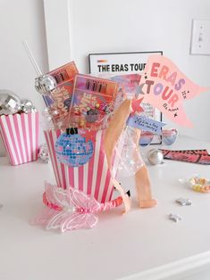 a pink and white striped bag with some candy in it sitting on a table next to a sign