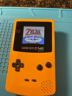 an orange game boy color sitting on top of a blue table