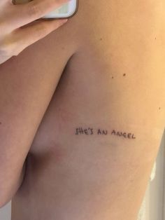 a person with a cell phone in their hand and some writing on the side of her body