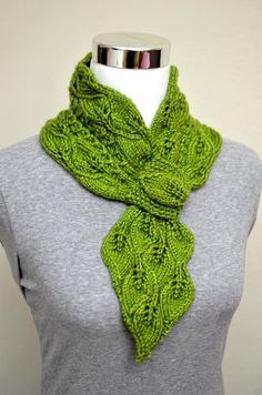 a green knitted scarf on a mannequin's head with a gray shirt underneath it