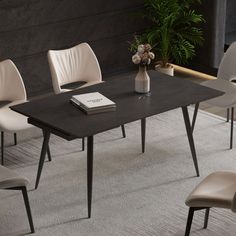 a black table with white chairs and a book on it next to a potted plant