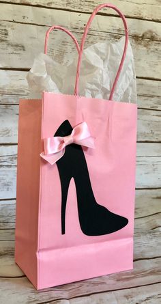 a pink paper bag with a black shoe on it and a pink ribbon around the handle