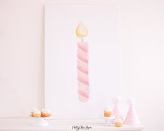 some cupcakes and a lit candle on a shelf in front of a white wall