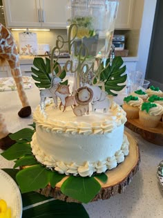 a white cake sitting on top of a table next to cupcakes