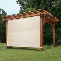 a wooden pergolan in the middle of a grassy area with trees behind it