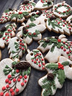 decorated cookies with holly leaves and pine cones on a wooden table, ready to be eaten