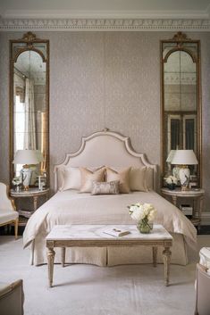 a large white bed sitting in a bedroom next to two tables