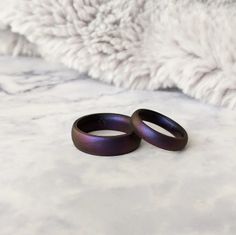 two purple rings sitting on top of a white blanket