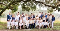 a large group of people are posing for a photo under the trees in front of them