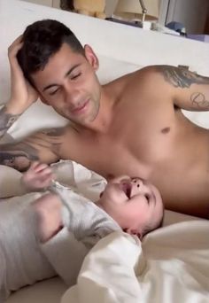 a man laying in bed next to a baby