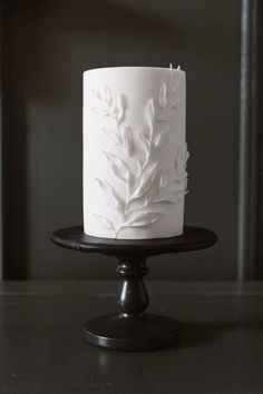 a white frosted cake sitting on top of a black plate next to a wall