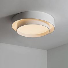 a circular light fixture mounted on the ceiling in a room with white walls and flooring