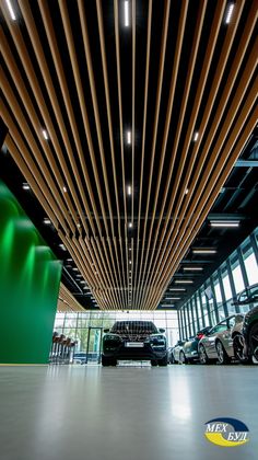 the inside of a car showroom with many cars parked in front of it and wood slats hanging from the ceiling