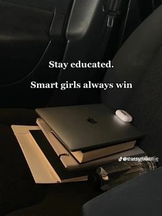 an apple laptop sitting on top of two books in the back seat of a car