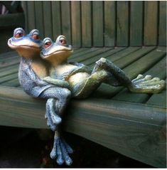 two frogs sitting on top of a wooden bench