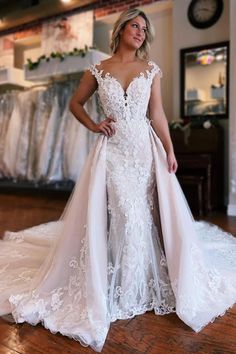 a woman in a white wedding dress standing on a wooden floor with her hands on her hips