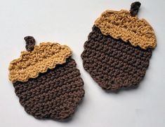 two crocheted acorns sitting on top of a white table next to each other