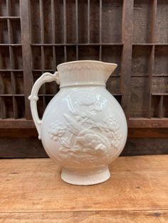 a white vase sitting on top of a wooden table