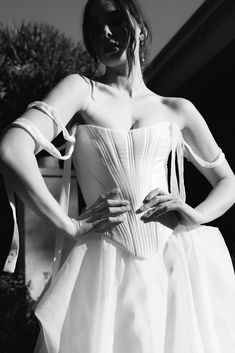 black and white photograph of woman in dress with hands on hips, looking at camera