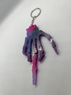 a keychain that has been made to look like a hand with purple and pink paint on it