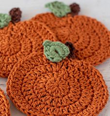 three crocheted pumpkin coasters sitting on top of a table