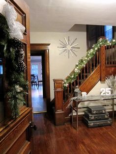 a living room filled with furniture and christmas decorations on top of a wooden floor next to a stair case